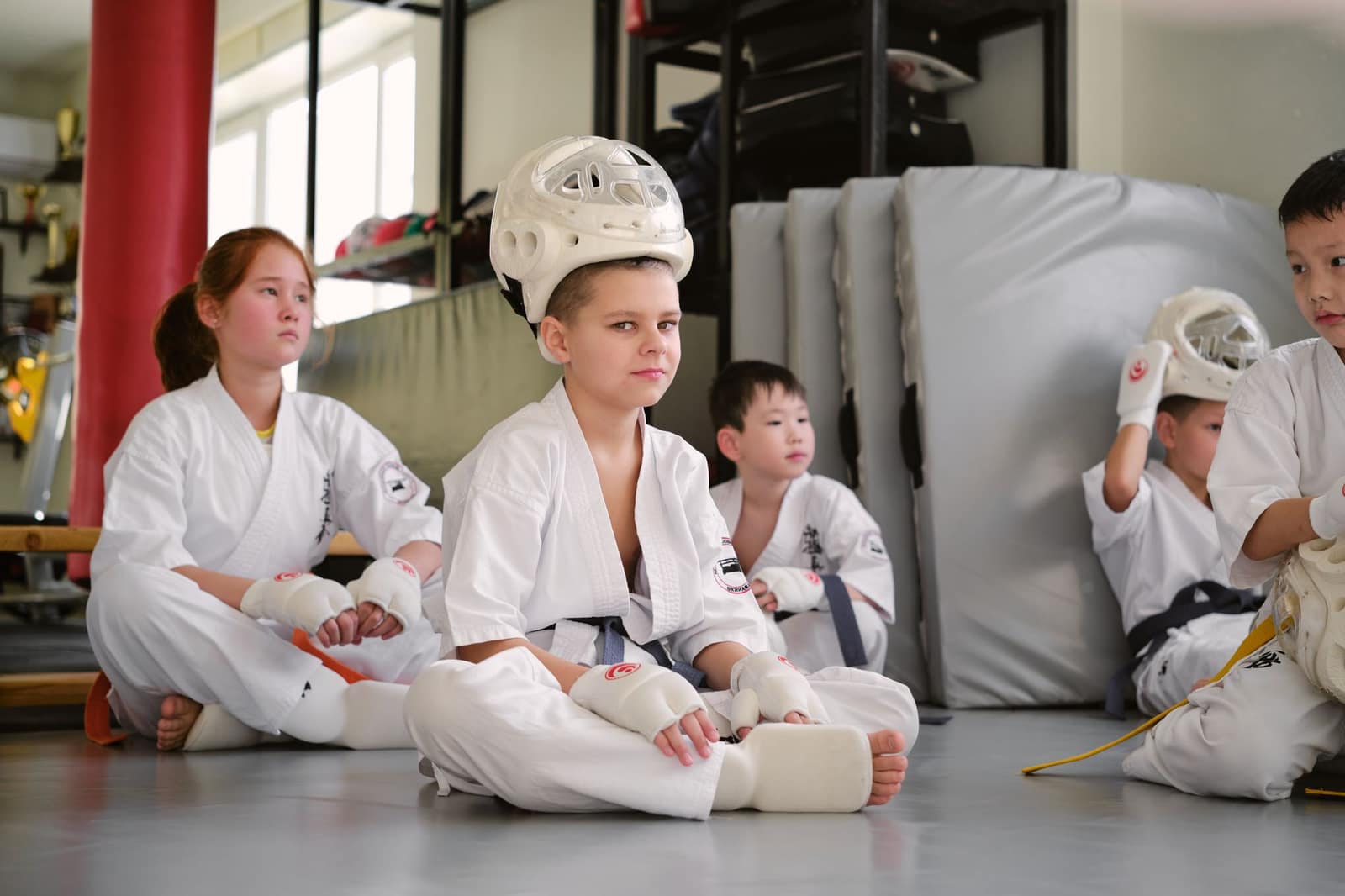 Kids in martial arts uniforms sitting in a dojo, preparing for judo class.